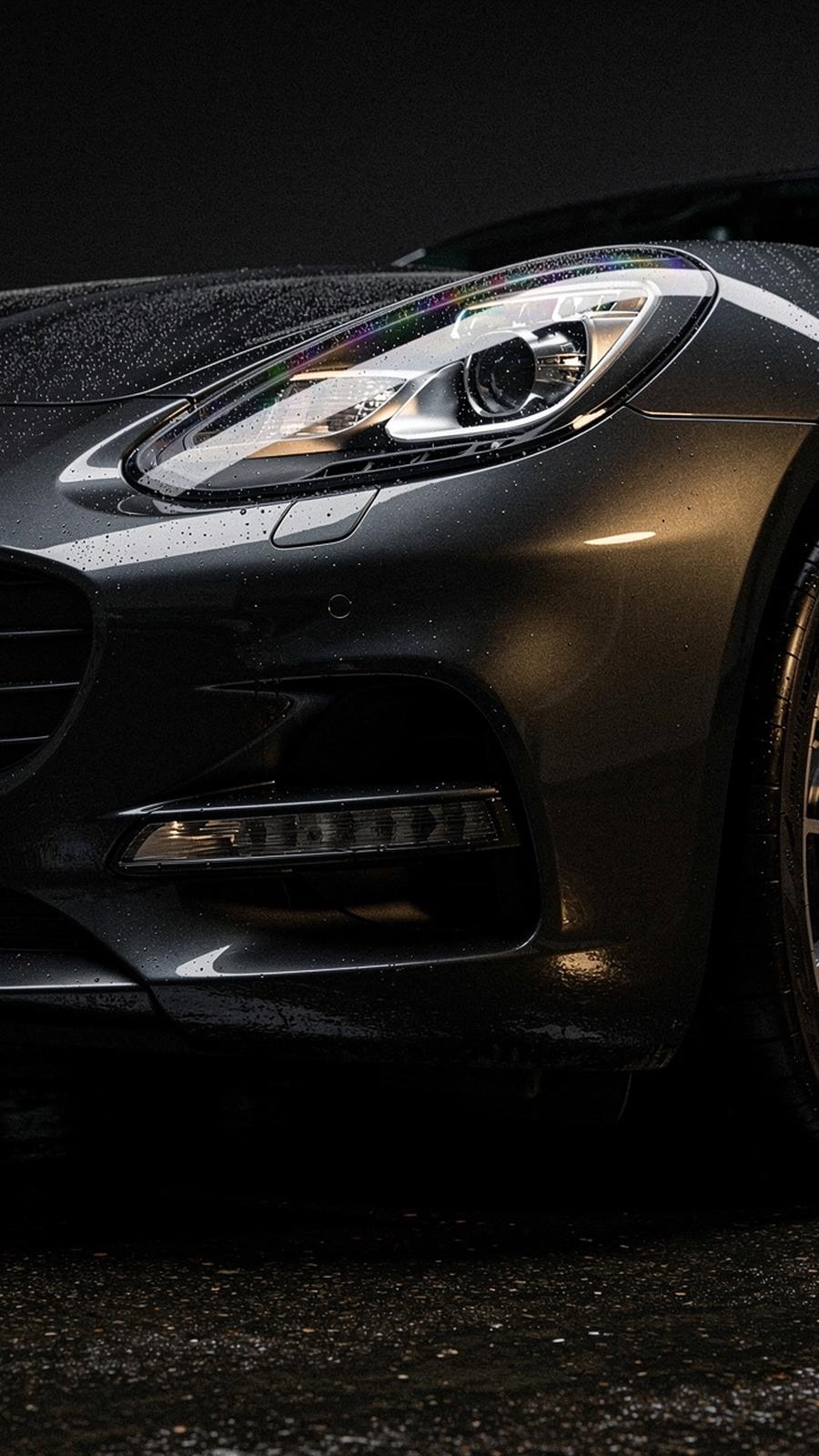 Close crop of a polished headlight and front wing on a dark luxury car