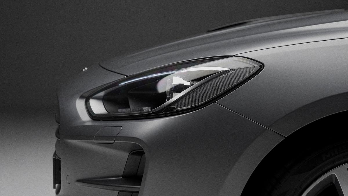 Close crop of a matte grey car headlight and front quarter panel
